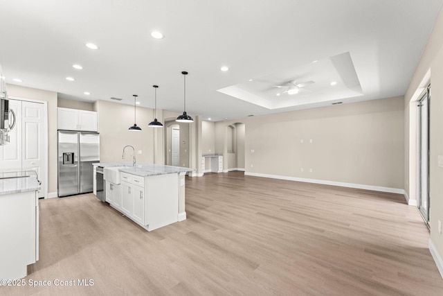 kitchen with stainless steel appliances, ceiling fan, a raised ceiling, recessed lighting, and white cabinets