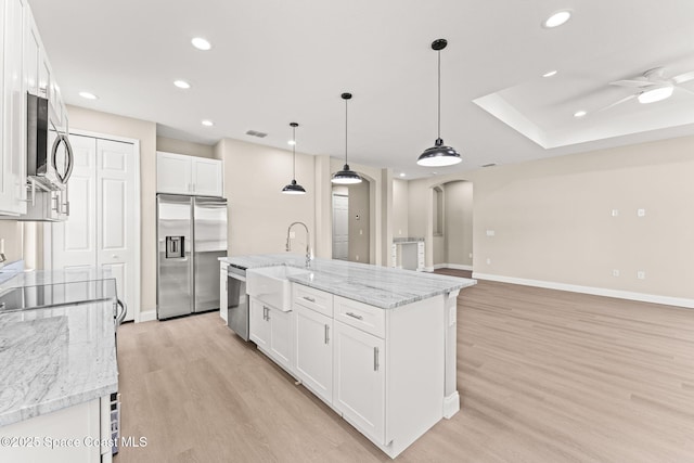 kitchen with appliances with stainless steel finishes, arched walkways, a sink, light wood-style floors, and recessed lighting