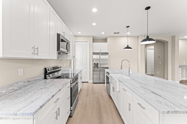 kitchen with appliances with stainless steel finishes, a sink, white cabinets, light wood-type flooring, and recessed lighting