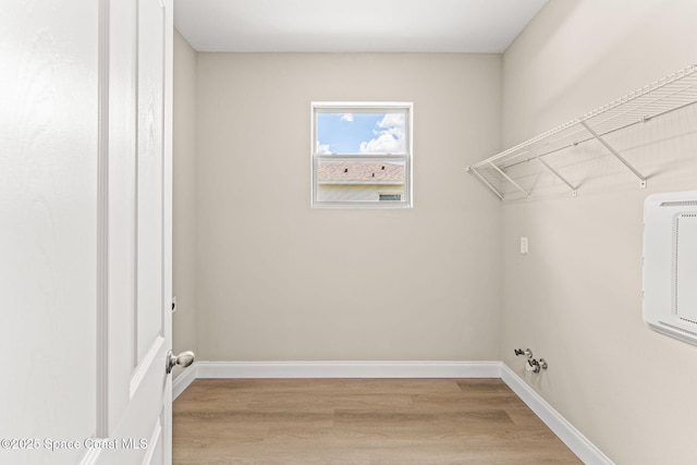 clothes washing area featuring light wood finished floors and baseboards