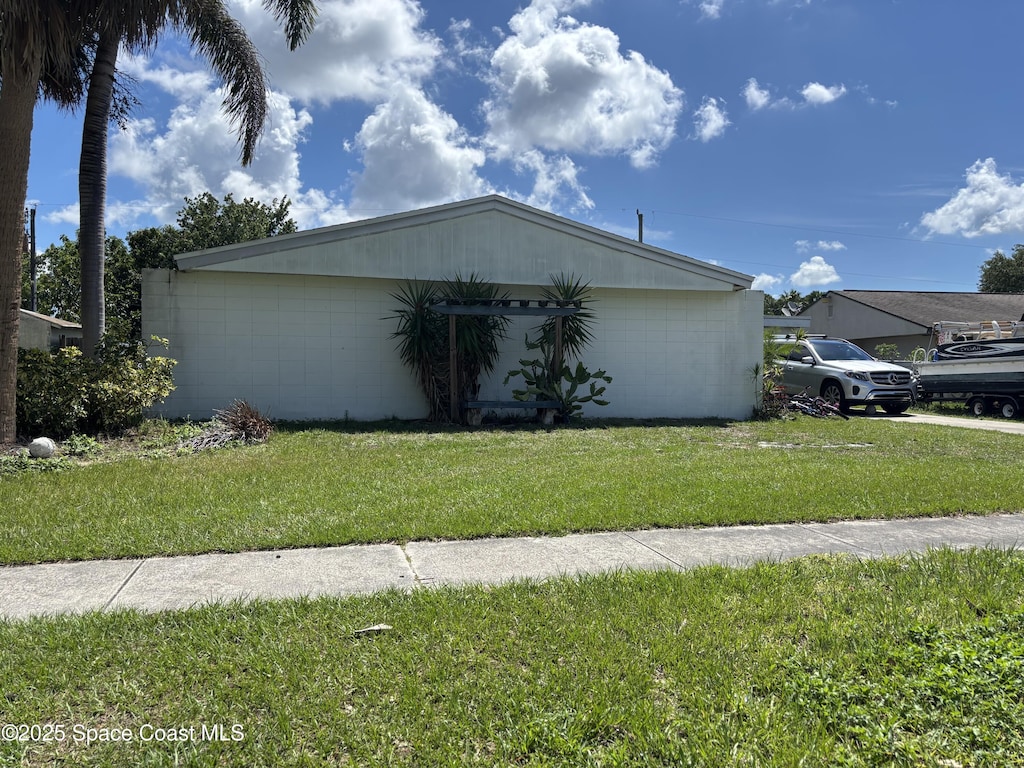 view of property exterior featuring concrete block siding and a lawn