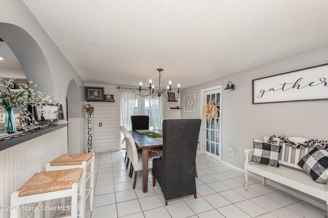 958 Beaumont Ln, Rockledge, FL 32955 - dining area featuring arched walkways, a chandelier, a textured ceiling, wainscoting, and light tile patterned floors