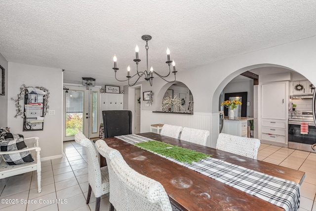 958 Beaumont Ln, Rockledge, FL 32955 - dining area featuring light tile patterned flooring, a chandelier, a textured ceiling, and arched walkways