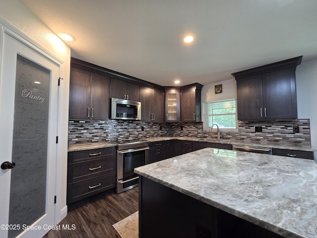 334 Dryden Cir, Cocoa, FL 32926 - kitchen featuring appliances with stainless steel finishes, light stone counters, dark wood-type flooring, a sink, and dark brown cabinetry