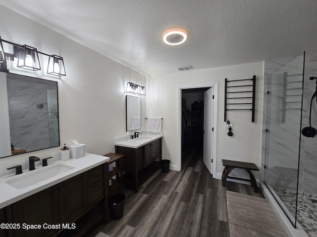 334 Dryden Cir, Cocoa, FL 32926 - full bathroom featuring a stall shower, wood finished floors, two vanities, a textured ceiling, and a walk in closet