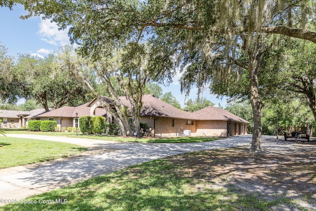 7793 Windover Way, Titusville, FL 32780 - ranch-style house featuring curved driveway and a front yard