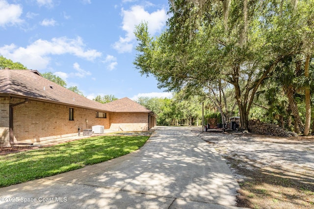 7793 Windover Way, Titusville, FL 32780 - view of home's exterior with brick siding, central AC, a shingled roof, and a lawn