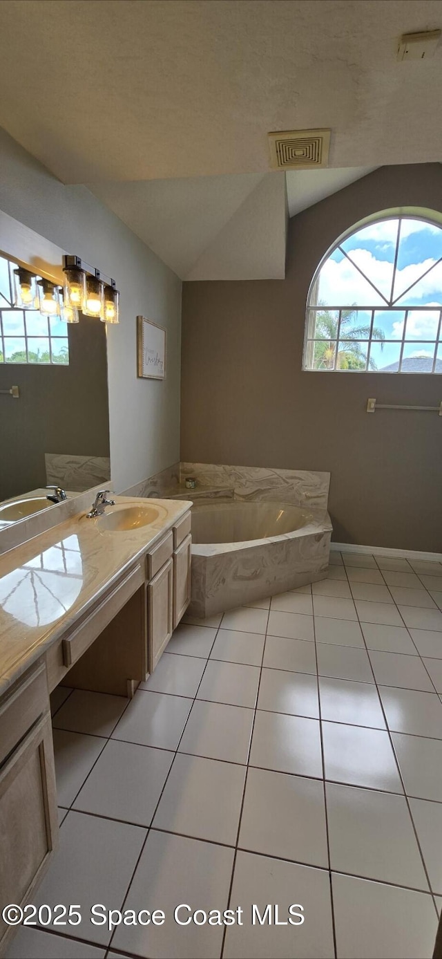 bathroom featuring tile patterned floors, double vanity, a bath, and vaulted ceiling