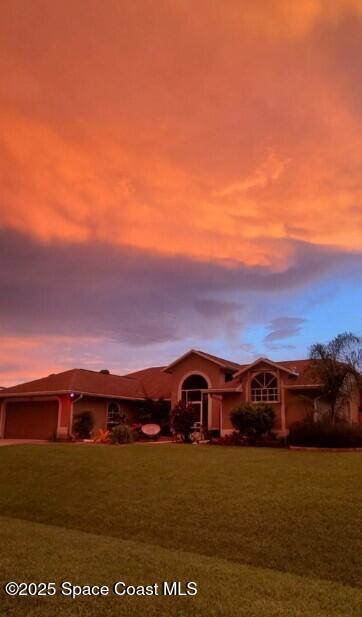 ranch-style home with a garage and a front lawn
