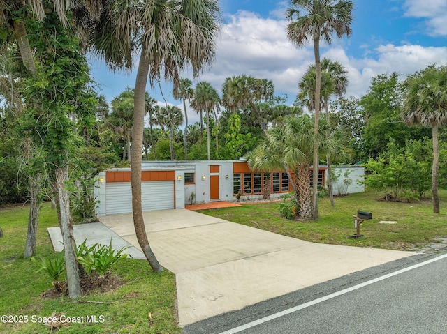 2318 Country Club Rd, Melbourne, FL 32901 - mid-century home featuring a front yard, a garage, driveway, and view of wooded area