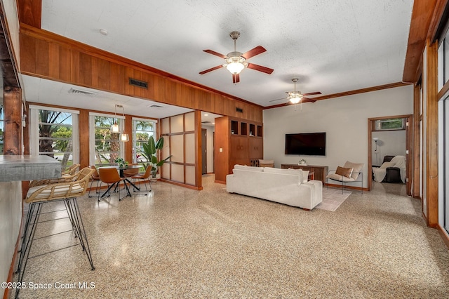 2318 Country Club Rd, Melbourne, FL 32901 - living room with wooden walls, ornamental molding, a ceiling fan, baseboards, and speckle patterned floor