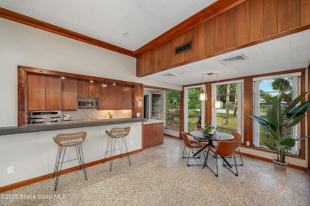 2318 Country Club Rd, Melbourne, FL 32901 - kitchen with appliances with stainless steel finishes, tasteful backsplash, brown cabinets, baseboards, and ornamental molding