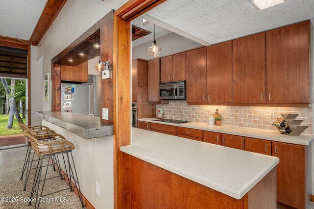 2318 Country Club Rd, Melbourne, FL 32901 - kitchen with appliances with stainless steel finishes, decorative backsplash, a peninsula, and brown cabinetry