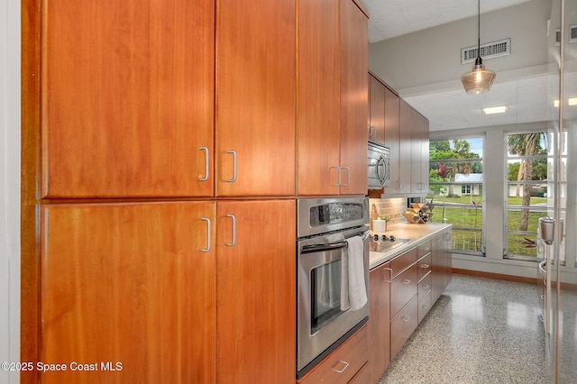 2318 Country Club Rd, Melbourne, FL 32901 - kitchen with appliances with stainless steel finishes, light countertops, pendant lighting, and brown cabinetry