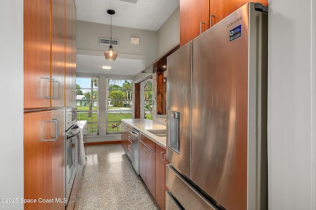 2318 Country Club Rd, Melbourne, FL 32901 - kitchen with stainless steel appliances, light countertops, decorative light fixtures, dark speckled floor, and brown cabinetry
