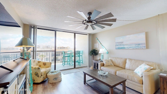 living area with floor to ceiling windows, a textured ceiling, wood finished floors, and a ceiling fan