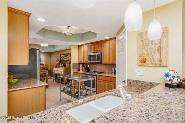 7008 Sevilla Ct Ph 505, Cape Canaveral, FL 32920 - kitchen featuring stainless steel appliances, a sink, decorative backsplash, light stone countertops, and a tray ceiling
