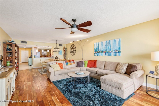 7008 Sevilla Ct Ph 505, Cape Canaveral, FL 32920 - living room with a ceiling fan, light wood-style flooring, a textured ceiling, and baseboards