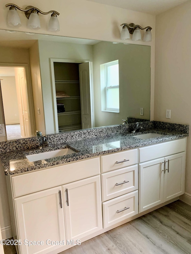 full bath with double vanity and wood finished floors
