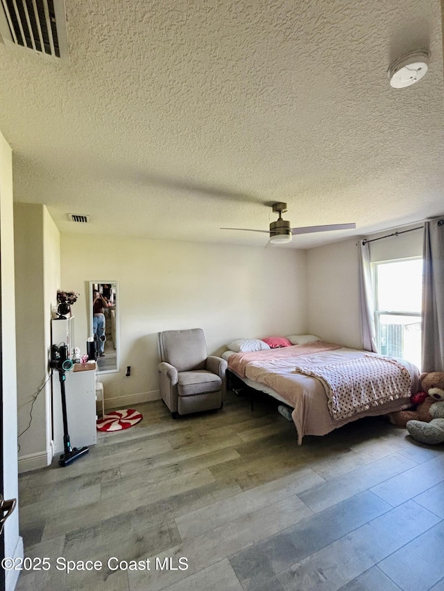 bedroom featuring a textured ceiling, wood finished floors, and a ceiling fan