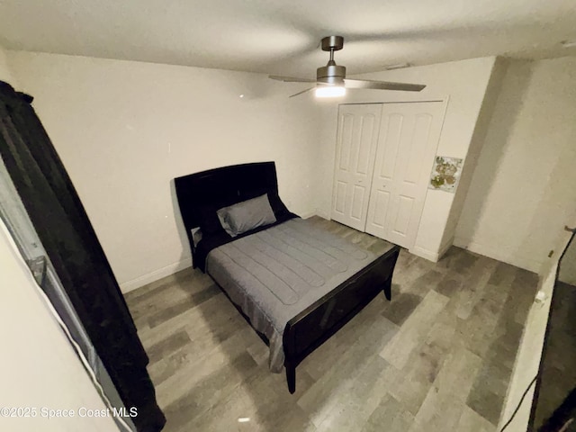 bedroom with wood finished floors, ceiling fan, a closet, and baseboards