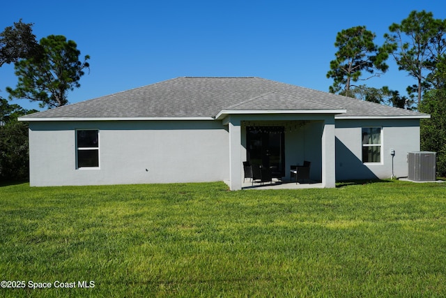 rear view of house featuring central AC unit, a lawn, a shingled roof, and stucco siding