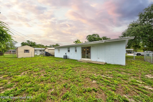 663 Bacon St, Cocoa, FL 32926 - back of property at dusk featuring a storage shed, central AC, an outbuilding, and concrete block siding