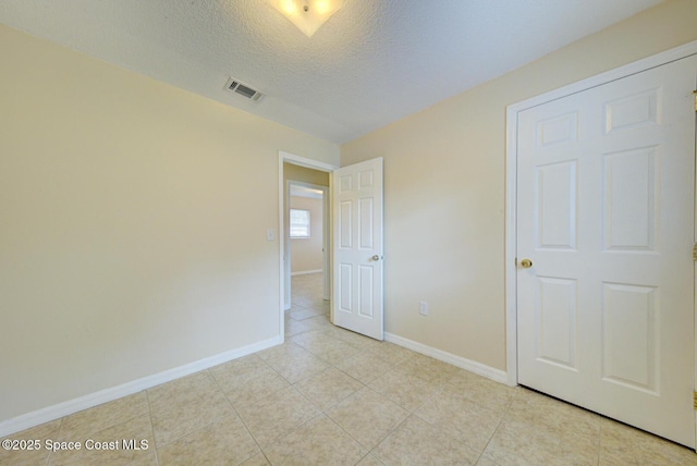 663 Bacon St, Cocoa, FL 32926 - unfurnished bedroom featuring baseboards, a textured ceiling, and light tile patterned flooring