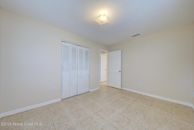 663 Bacon St, Cocoa, FL 32926 - unfurnished bedroom featuring a closet, baseboards, light tile patterned floors, and a textured ceiling