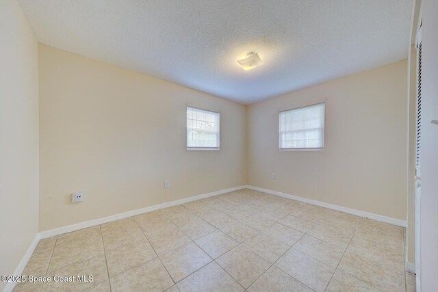 663 Bacon St, Cocoa, FL 32926 - spare room with plenty of natural light, light tile patterned flooring, a textured ceiling, and baseboards