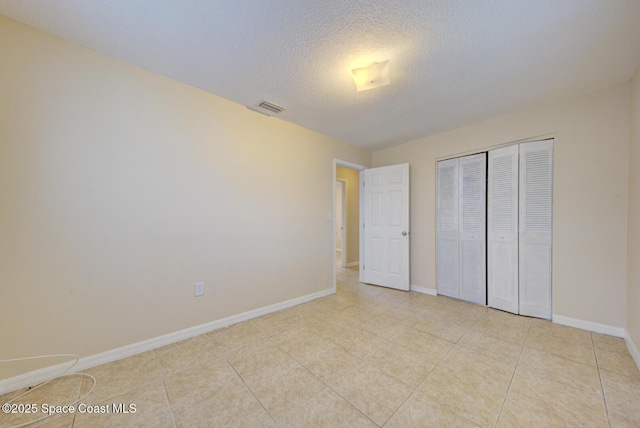 663 Bacon St, Cocoa, FL 32926 - unfurnished bedroom with baseboards, a closet, a textured ceiling, and light tile patterned flooring