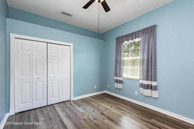 unfurnished bedroom featuring wood finished floors, a closet, and baseboards