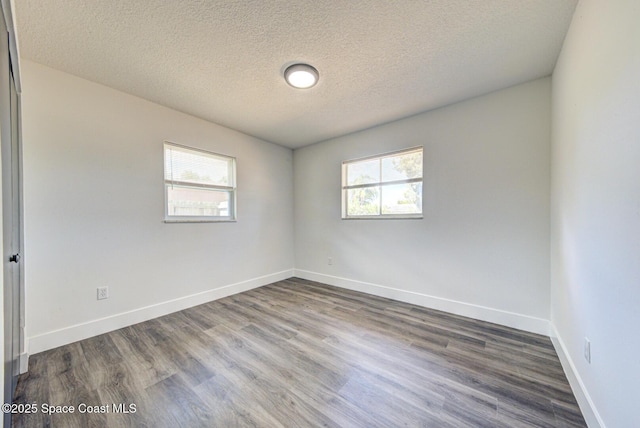 empty room featuring plenty of natural light, a textured ceiling, dark wood-style flooring, and baseboards