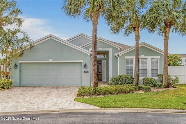 view of front of property featuring stucco siding, an attached garage, and decorative driveway