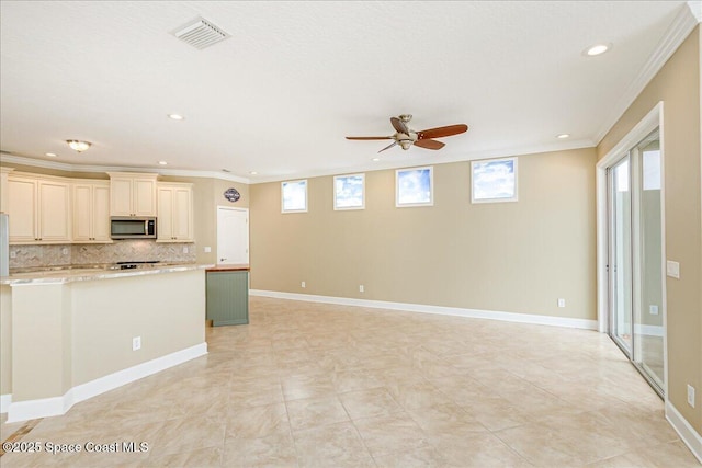 kitchen with stainless steel microwave, a ceiling fan, recessed lighting, cream cabinets, and tasteful backsplash