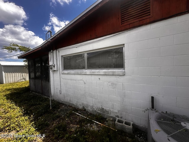 view of side of property featuring concrete block siding and cooling unit