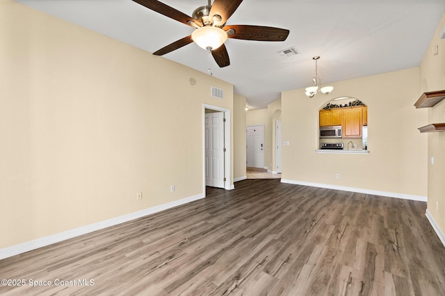3848 Lexmark Ln Unit 307, Rockledge, FL 32955 - unfurnished living room featuring a ceiling fan, wood finished floors, a chandelier, arched walkways, and baseboards