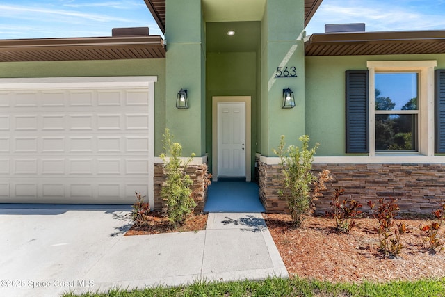 563 Holmes Ave NW, Palm Bay, FL 32907 - view of exterior entry with stucco siding, a garage, and stone siding