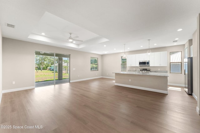 563 Holmes Ave NW, Palm Bay, FL 32907 - unfurnished living room featuring healthy amount of natural light, wood finished floors, recessed lighting, ceiling fan, and baseboards
