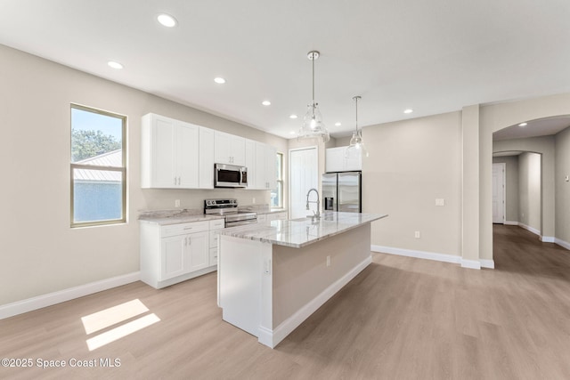 563 Holmes Ave NW, Palm Bay, FL 32907 - kitchen with stainless steel appliances, arched walkways, light wood-style flooring, a sink, and white cabinets