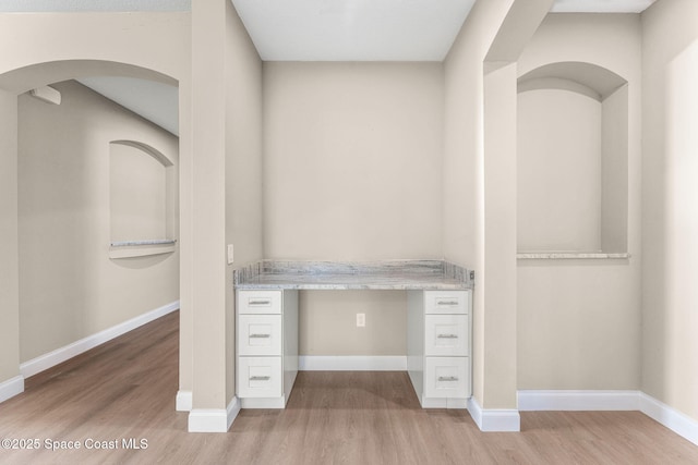 563 Holmes Ave NW, Palm Bay, FL 32907 - unfurnished office featuring light wood finished floors, built in study area, baseboards, and arched walkways