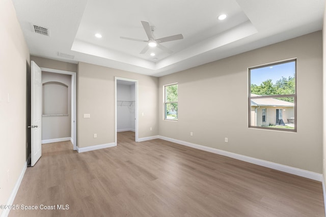 563 Holmes Ave NW, Palm Bay, FL 32907 - unfurnished bedroom featuring a tray ceiling, light wood-style floors, recessed lighting, baseboards, and a spacious closet