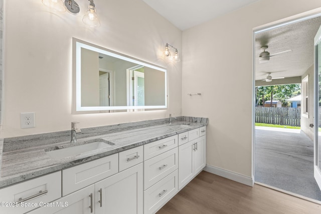 563 Holmes Ave NW, Palm Bay, FL 32907 - full bathroom featuring wood finished floors, a ceiling fan, baseboards, and double vanity