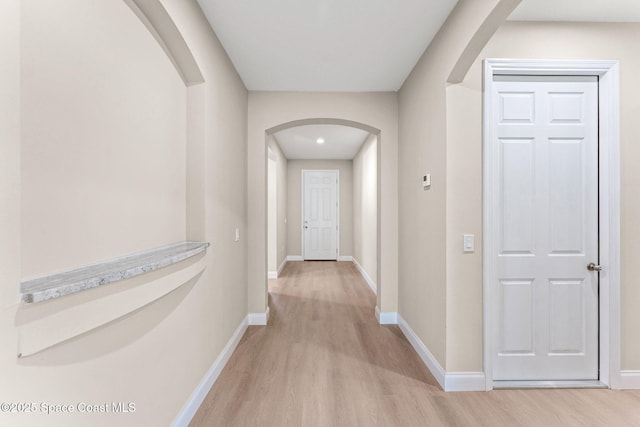 563 Holmes Ave NW, Palm Bay, FL 32907 - hall featuring arched walkways, light wood-style flooring, and baseboards