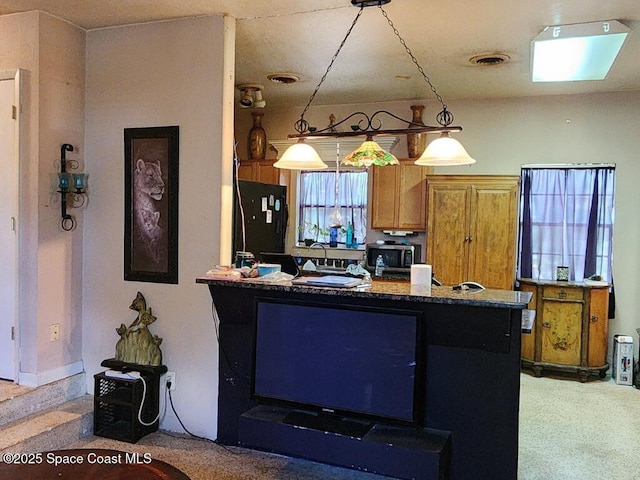 kitchen with freestanding refrigerator, stainless steel microwave, pendant lighting, brown cabinets, and a peninsula
