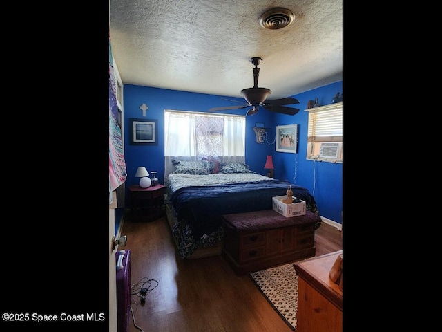 bedroom with a textured ceiling, wood finished floors, and a ceiling fan