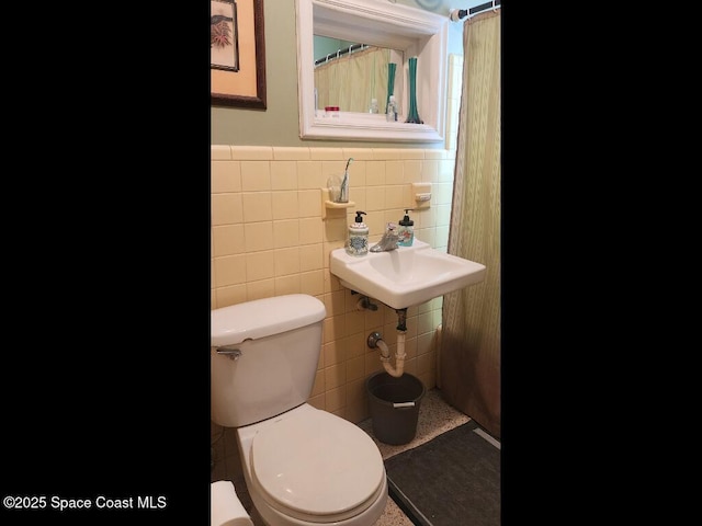 bathroom with tile walls, toilet, and wainscoting