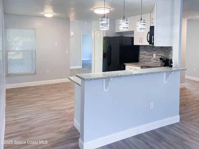 544 Plumbago Rd NW, Palm Bay, FL 32907 - kitchen with black appliances, a peninsula, a breakfast bar area, light stone countertops, and backsplash