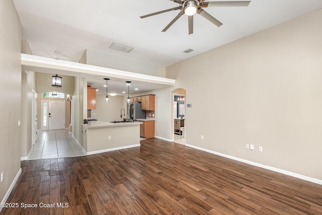 1536 Grand Isle Blvd, Melbourne, FL 32940 - unfurnished living room featuring a ceiling fan, arched walkways, wood finished floors, a sink, and baseboards