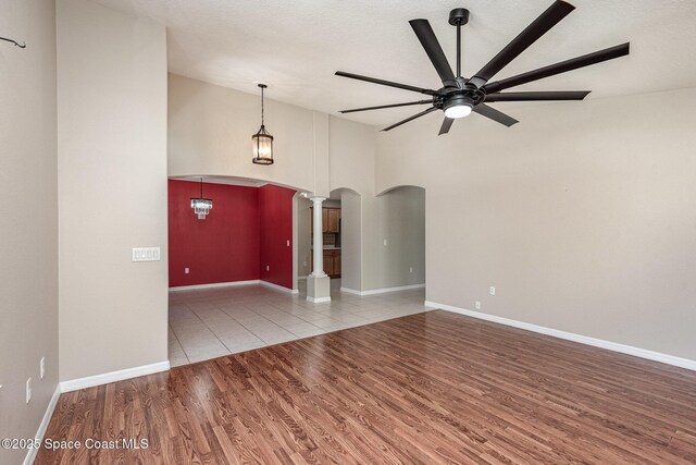 1536 Grand Isle Blvd, Melbourne, FL 32940 - spare room featuring arched walkways, decorative columns, a ceiling fan, wood finished floors, and baseboards